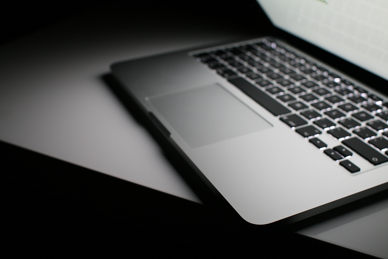 机の上のMacBook Proのモノクロ写真