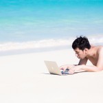 砂浜でMacBook Airで仕事をする男性