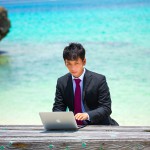 海でMacBook Proを使うスーツの男性